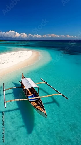Turquoise water laps the sandy beach where a boat rests under the clear tropical sky, suggesting a summer vacation on a beautiful island