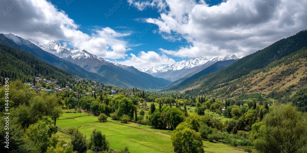 Naklejka premium Mountain valley with village, lush green meadows and snow-capped peaks, a scenic landscape, suitable for showcasing nature's beauty