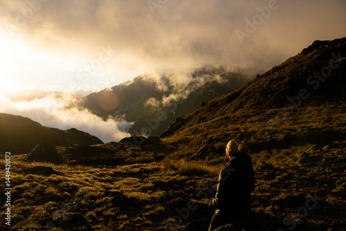 Female hiker bathed in sunlight, mountains,, New Zealand