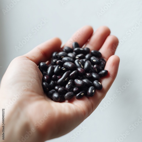 Hand offering a portion of nutritious black beans against a clean backdrop