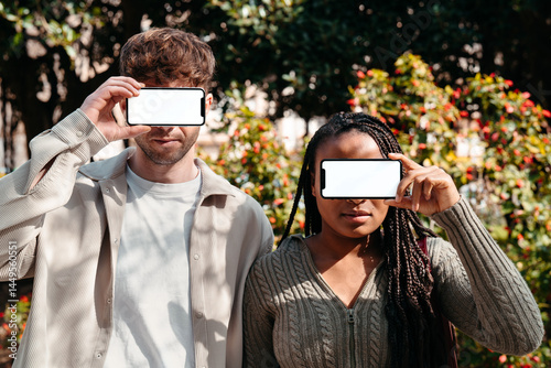 Anonymous man and woman with blank mobile phones on their faces