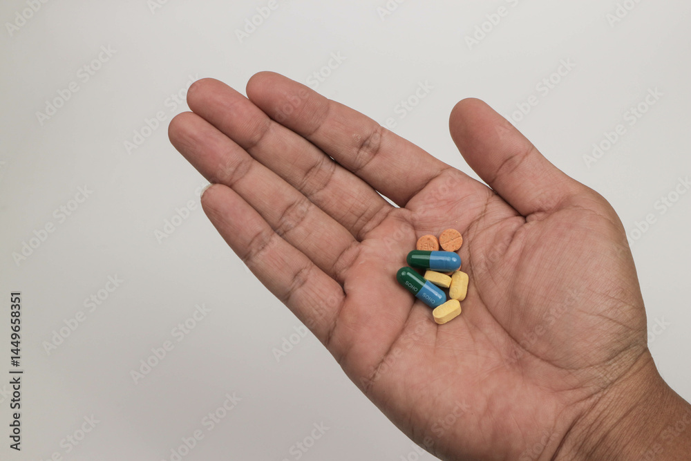 Close-up hand holding a variety of colorful pills and capsules, including round tablets on a plain background. Close-up hand holding a variety of colorful pills and capsules, including round tablets on a plain background.