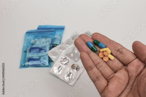 Close-up of a hand holding various pills and tablets with blurred medical supplies in the background