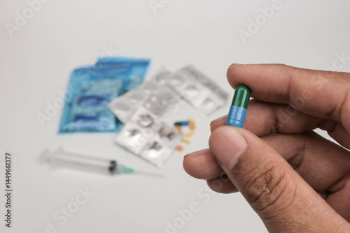 Close-up of a hand holding a single tablet with blurred medical supplies in the background