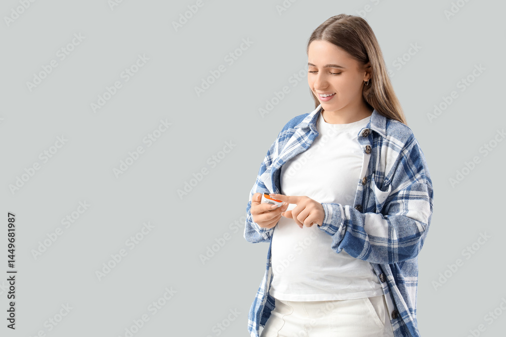 Young pregnant woman with gestational diabetes using glucometer on light background Young pregnant woman with gestational diabetes using glucometer on light background