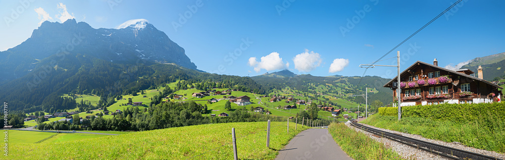 walkway beside railroad Grindelwald, chalet with geranium flowers, Eiger and Wetterhorn mountain