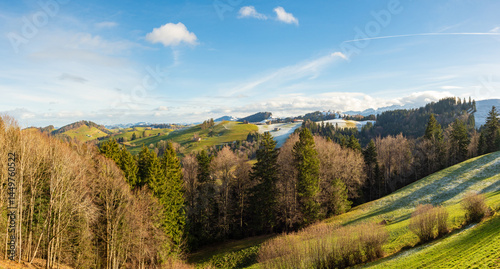 Mogelsberg, Switzerland - January 1st 2024: View over fields and forests towards snow coverd hills and mountains