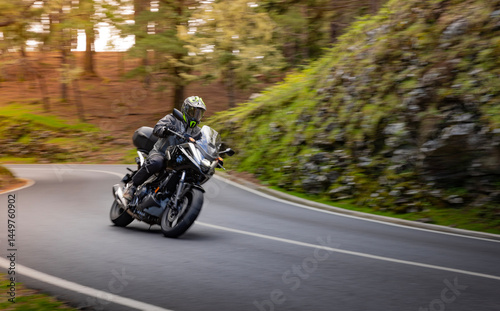 Fototapeta Naklejka Na Ścianę i Meble -  Driver riding motorcycle on empty asphalt road, blurred motiion, spring mountains