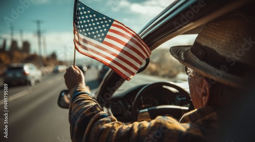 Senior Caucasian man in a car, holding an American flag out the window.  Patriotic road trip vibes.