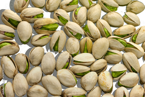 Obraz na płótnie Pistachios nuts background. Healthy food. Roasted green pistachios in open shells on a white background with a shadow. Full frame filling. Lots of nuts, almonds pistachios. w salonie