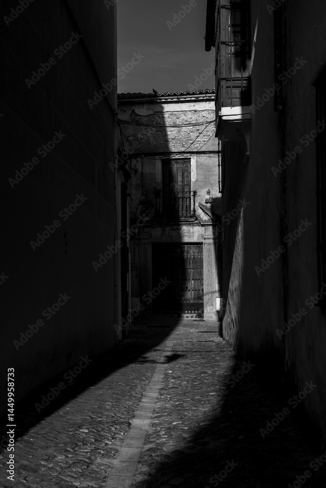 black and white picture of an old town alley of Ronda, partially in shade black and white picture of an old town alley of Ronda, partially in shade