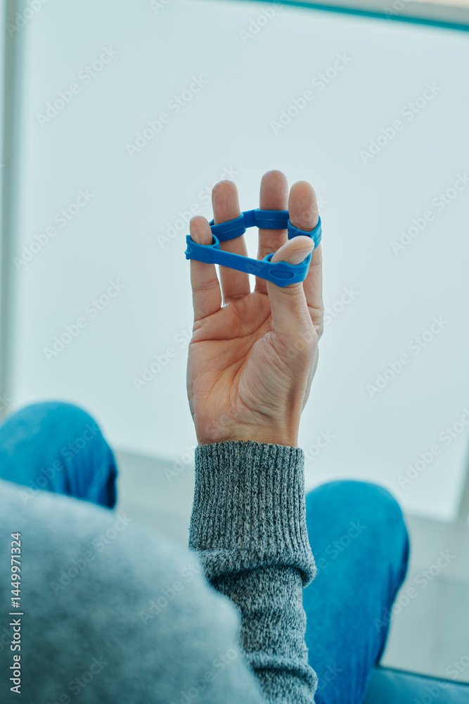 man uses an elastic band to exercise his fingers
