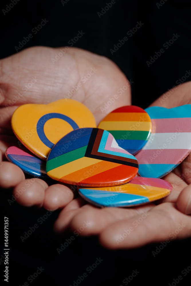 badges with different LGBTQ flags in his hands