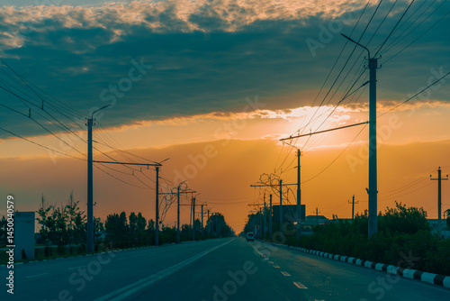A road with a lot of power lines and a sunset in the background