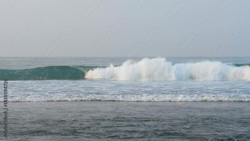 Powerful ocean wave gradually forming, breaking against sandy shore with white foam. Perfect surfing wave. Wave creating display of nature raw energy Powerful ocean wave gradually forming, breaking against sandy shore with white foam. Perfect surfing wave. Wave creating display of nature raw energy