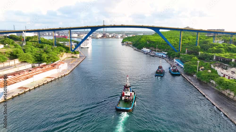 Tugboats sailed on Sint Anna Bay with Koningin Julianabrug bridge in Willemstad historic city center, Curacao. Historic Willemstad is a UNESCO World Heritage Site. 