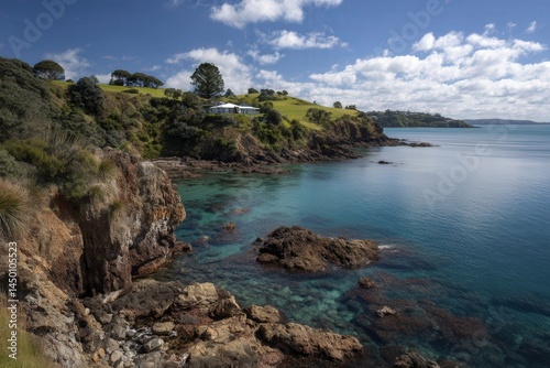 Scenic coastal landscape with rocky cliffs and clear blue sea under a vibrant sky.