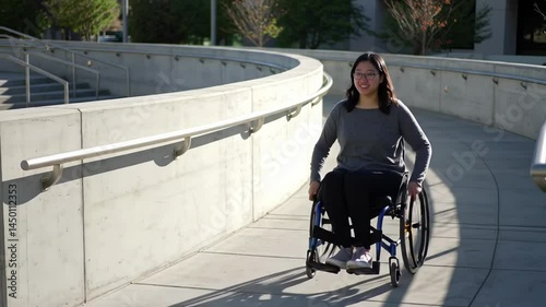 Smiling Asian Woman in Wheelchair Navigating Accessible Outdoor Concrete Ramp