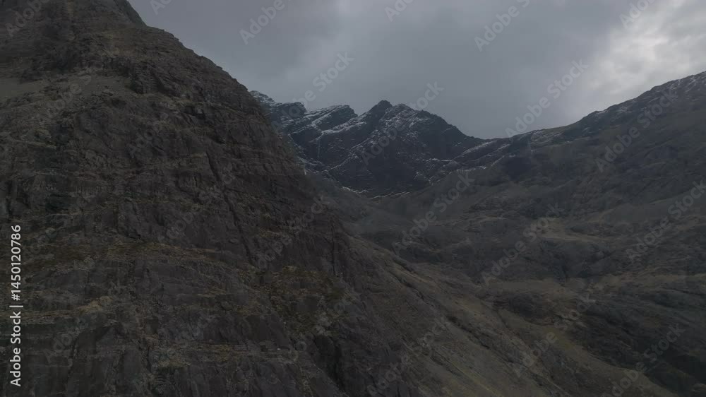 Drone reveal of the Cuillin mountains on Scotland’s Isle of Skye under dramatic clouds with snowy peaks Drone reveal of the Cuillin mountains on Scotland’s Isle of Skye under dramatic clouds with snowy peaks