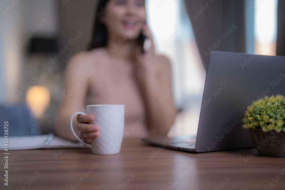 Young woman enjoying a coffee break while working from home, using her laptop and smartphone. Embracing a moment of relaxation in her cozy home office during the workday Young woman enjoying a coffee break while working from home, using her laptop and smartphone. Embracing a moment of relaxation in her cozy home office during the workday