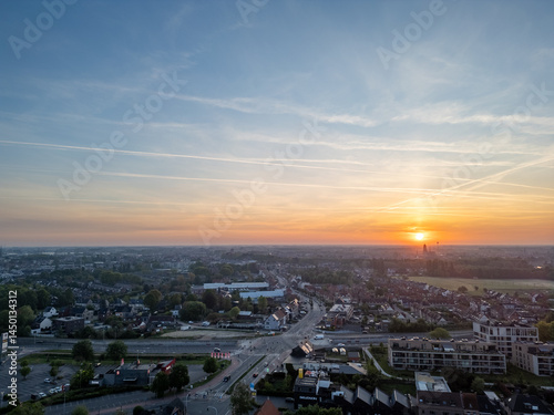 A breathtakingly beautiful sunset is casting warm hues over a serene and picturesque townscape under a dramatic sky