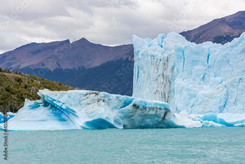 Patagonia famous glacier Perito Moreno in Argentina. Blue ice blocks falling in the lake at the bottom of huge patagonian glacier, part of the Patagonia ice fields. Lake full of icebergs