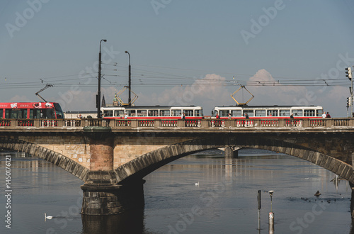 Historic bridge in Prague with red trams