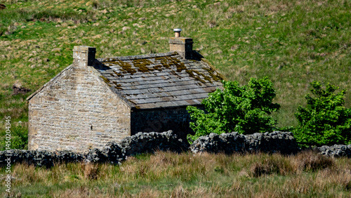 A remote abandoned and derelict stone built cottage with slate tiled roof in the Yorkshire Dales national park