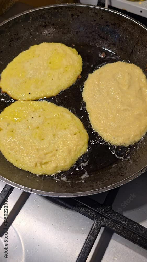 Several potato pancakes are shown frying in a pan with hot oil. Some appear golden and crispy, while others are still cooking, illustrating the process of making this popular and delicious dish. 4k Several potato pancakes are shown frying in a pan with hot oil. Some appear golden and crispy, while others are still cooking, illustrating the process of making this popular and delicious dish. 4k