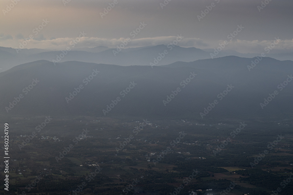 Fototapeta premium Aerial view of village of yelagiri from the mountain top, a top view, mountains covered with mist. Yelagiri hill station, nearest to Chennai