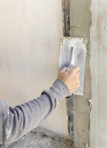 Obraz na płótnie Craftsman uses a float trowel and cement to plaster a house wall. Construction process w salonie