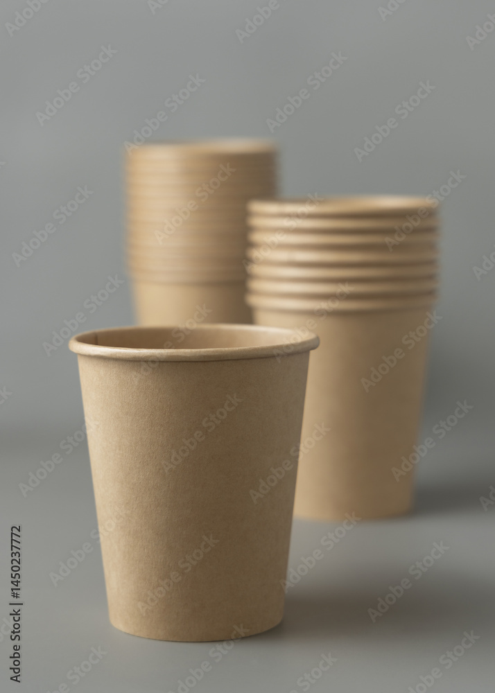 Disposable beige kraft paper cups on a gray closeup, mockup. No plastic and sustainable lifestyle