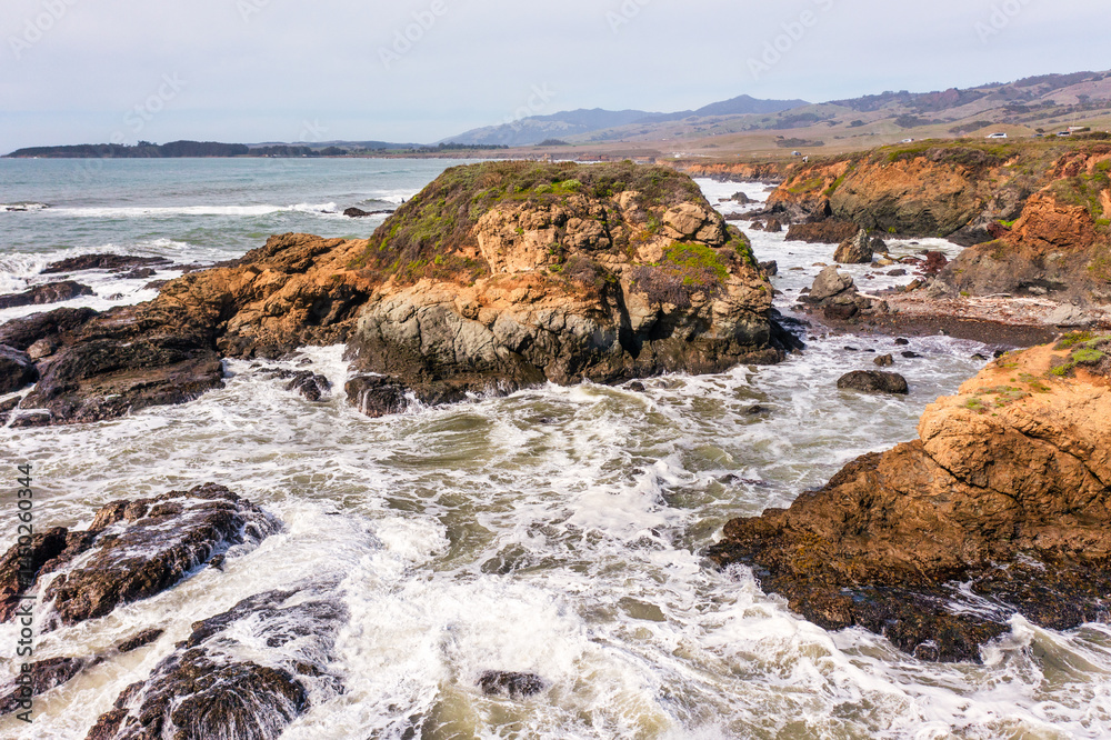 Fototapeta premium Stunning coastal landscape along California's Highway 1, featuring rugged rocky formations, and the vast blue ocean. A breathtaking natural scene showcasing the raw beauty of the Pacific coastline