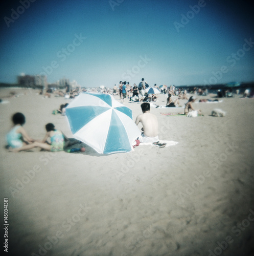 Tourists on the beach with beach umbrella, Coney Island, Brooklyn, United States 