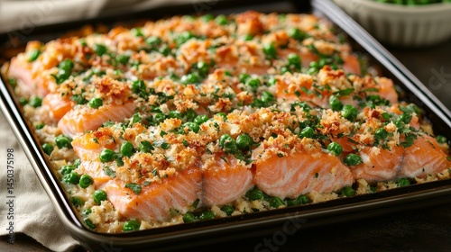 Baked salmon fillet topped with fresh herbs green peas and crunchy breadcrumb crust in a baking tray close-up view
