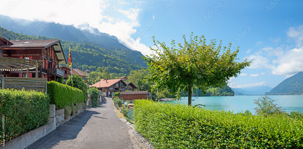 lakeside walkway Iseltwald with hedges and chalets, tourist resort lake Brienzersee.