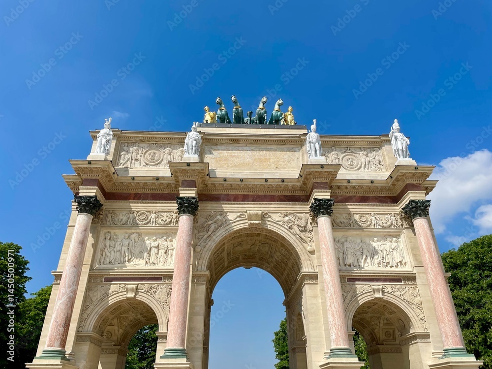 Obraz premium Close-up view of the Arc de Triomphe du Carrousel in Paris on a sunny day, showcasing ornate sculptures and classical architecture near the Louvre Museum.