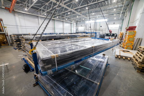 Crane lifting stack of solar panels in warehouse