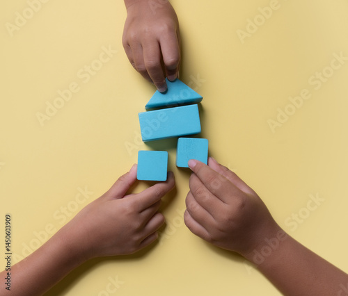 Child's hand close up playing building Housebuilding blocks and family home