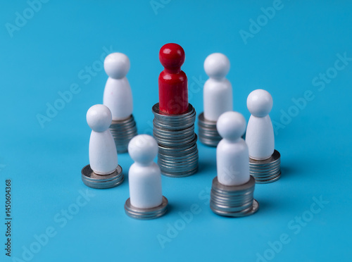 Red wood figurine on top of stack of coins.