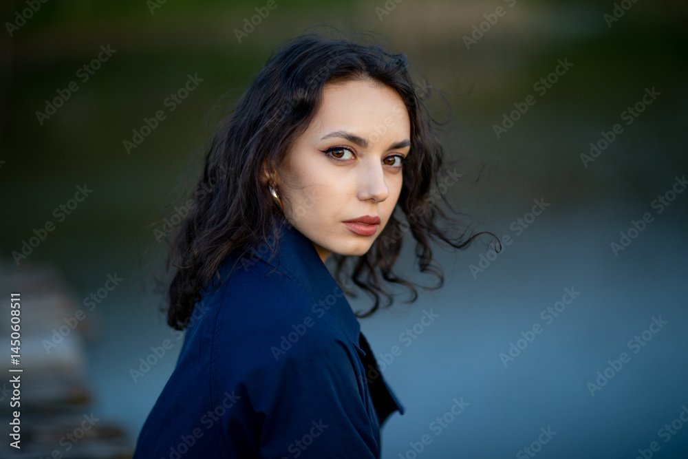 beautiful brunette european girl in blue trench coat at nature. Young lady with beautiful face and lips.