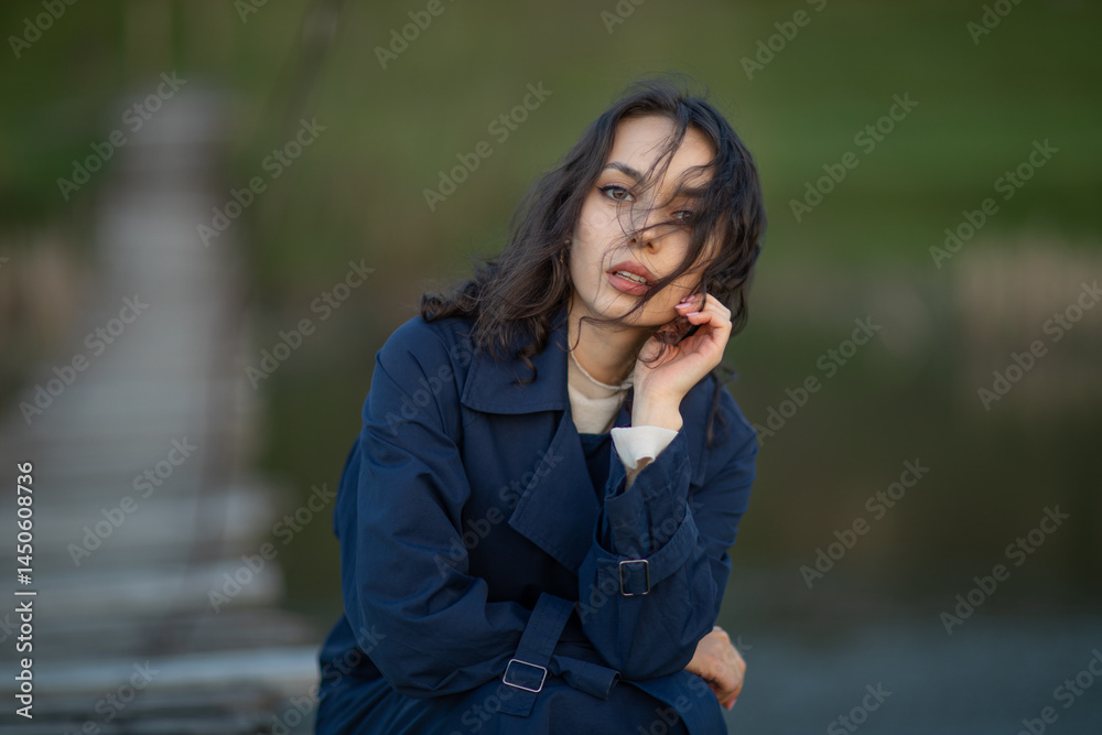 beautiful brunette european girl in blue trench coat at nature. Young lady with beautiful face and lips.