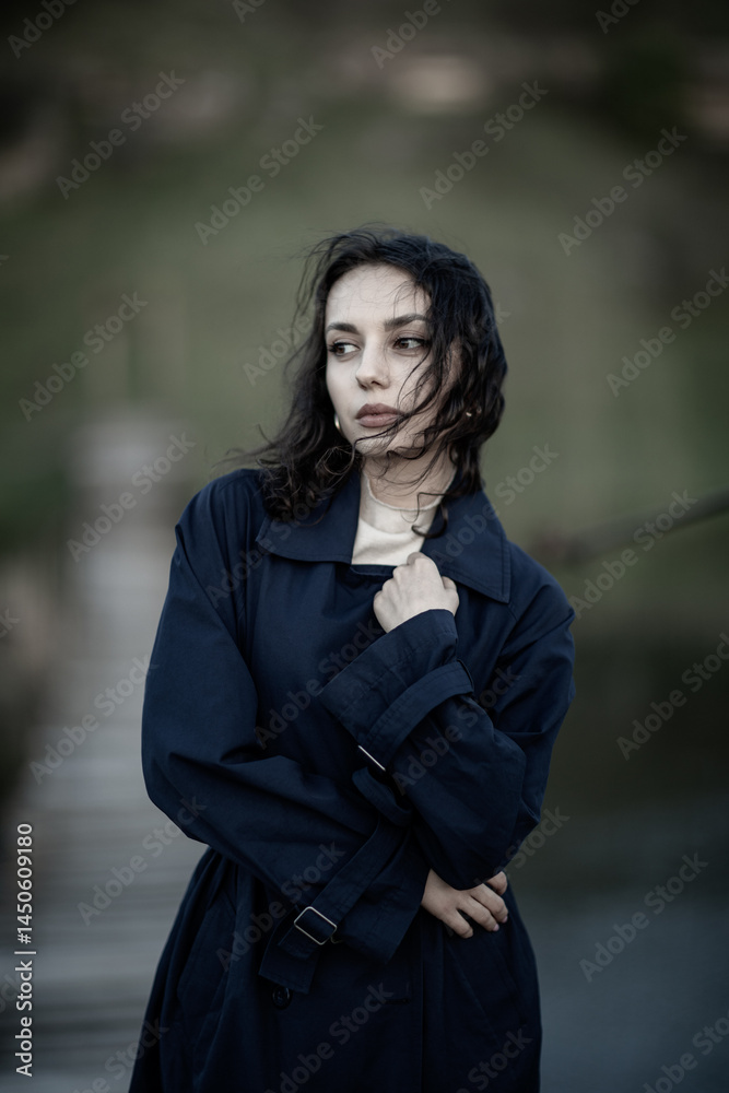 beautiful brunette european girl in blue trench coat at nature. Young lady with beautiful face and lips.