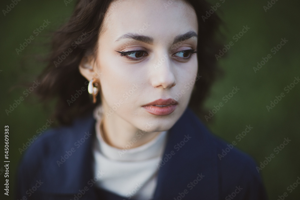 beautiful brunette european girl in blue trench coat at nature. Young lady with beautiful face and lips.