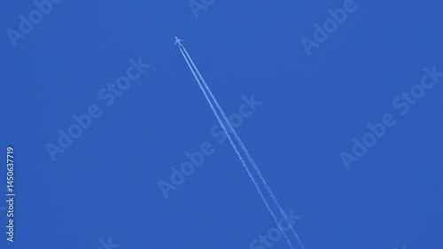 a plane flies high in the blue sky with vapour trail