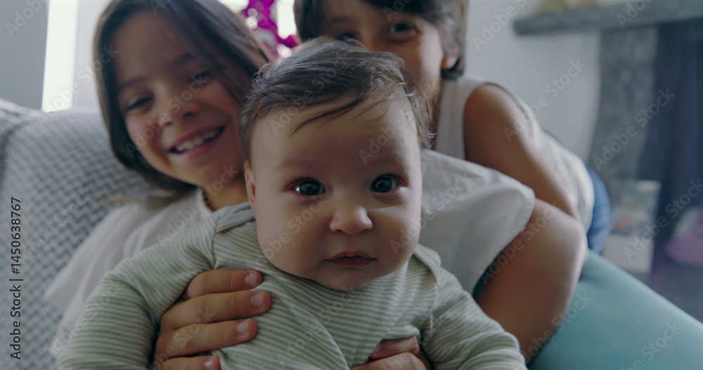 Fototapeta premium Siblings with baby, girl holding baby, boy leaning close, family bonding on couch, happy children, cozy home setting, sibling love, casual moment, bright indoor scene-SD 480p