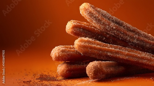 A tempting stack of warm, freshly fried churros, generously coated in a sweet sugary topping against a warm, inviting orange backdrop.