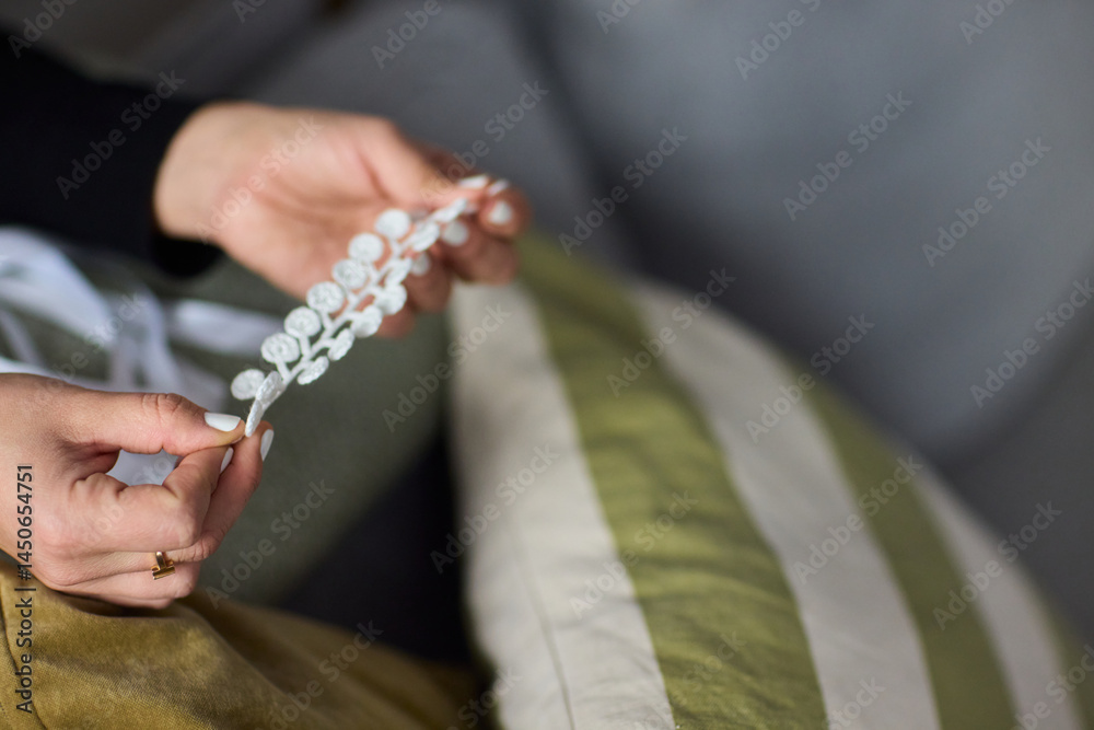 Closeup of hands with colorful beads on a cozy couch, showcasing handmade decor elegance