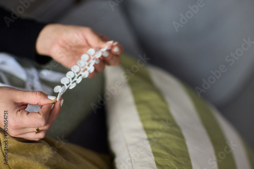 Obraz na płótnie Closeup of hands with colorful beads on a cozy couch, showcasing handmade decor elegance w salonie