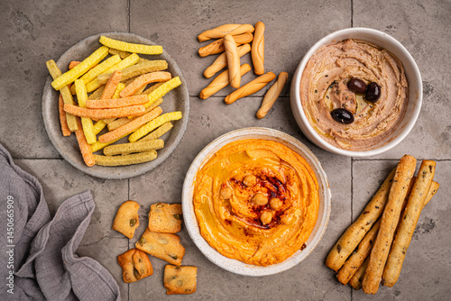 Obraz na płótnie Various hummus dips in different colours. Hummus with dry crackers, top view. Vegan and traditional hummus as healthy and vegan snack. w salonie